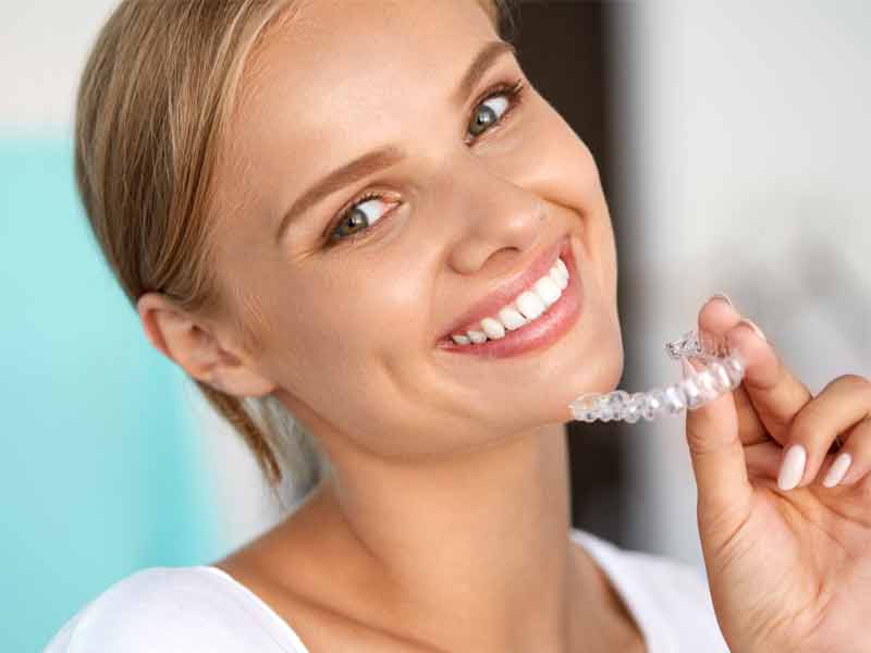 Woman holding an Invisalign clear aligner